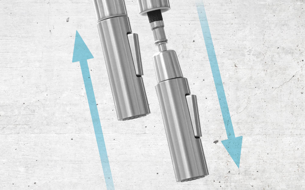Obraz przedstawia dwa cylindryczne elementy metalowe z uchwytami, ustawione pionowo na tle betonowej powierzchni. Obok nich znajdują się niebieskie strzałki skierowane w przeciwnych kierunkach.