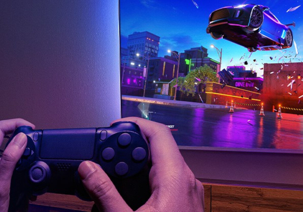 PHILIPS 75MLED920 HDMI 2.1 VRR 144Hz granie, telewizor zawieszony na ścianie w pomieszczeniu, osoba trzymająca kontroler