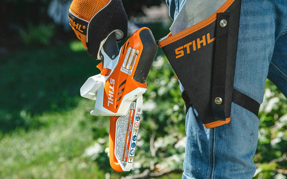 Piła akumulatorowa STIHL GTA 26 ogród osoba trzyma piłę w dłoni w tle trawnik cięcie gałęzi wszechstronne zastosowanie zasilanie akumulatorowe