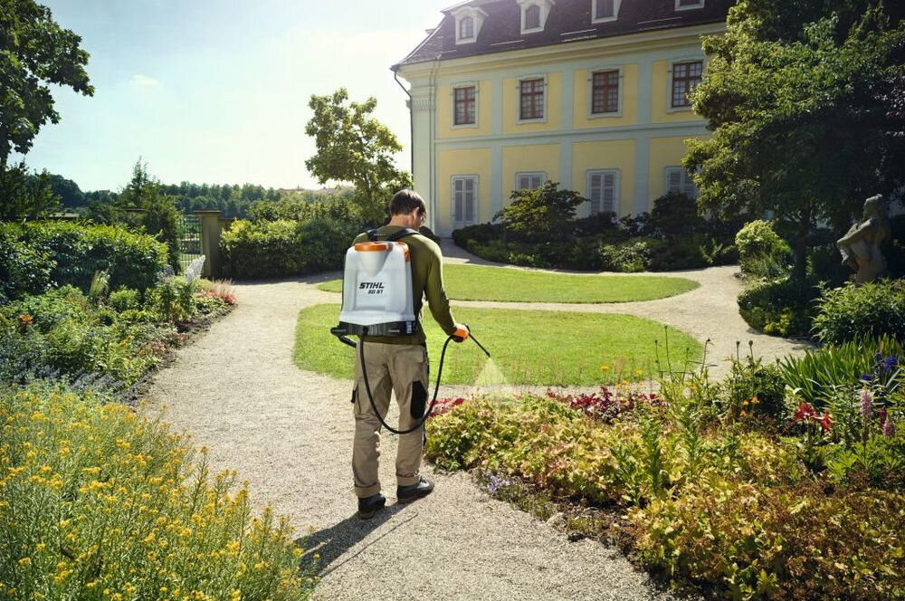 Opryskiwacz plecakowy STIHL SG 51 12L, plecakowy, bar, ciśnienie, pompa, mężczyzna opryskiwuje trawnik przy pałacu