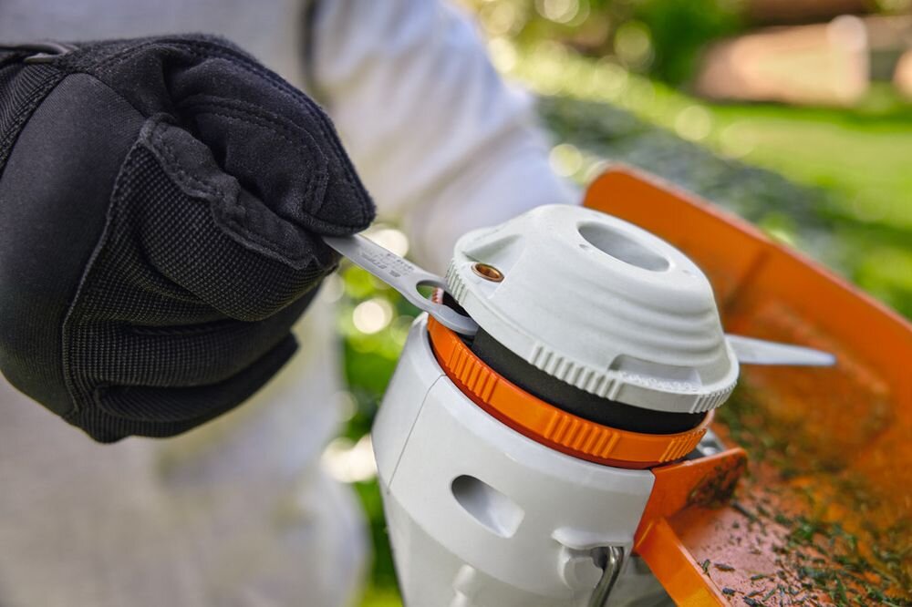 Nożyki STIHL 40080071000 (8 szt.), tworzywo, głowice, polycut, ostrze, osoba w rękawiczkach wymienia ostrza w głowicy tnącej