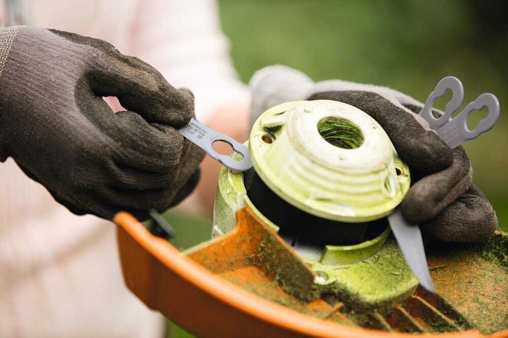 Nożyki STIHL 40080071000 (8 szt.), narzędzia, cięcie, praca, montaż, osoba w rękawiczkach wymienia ostrza w głowicy tnącej