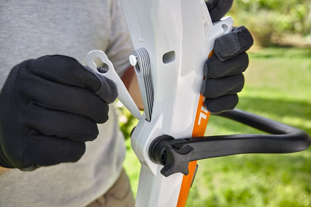 Nożyki STIHL 40080071000 (8 szt.), polycut, model, części, oryginalne, osoba w rękawiczkach sięga po jedno z ostrzy na uchwycie podkaszarki
