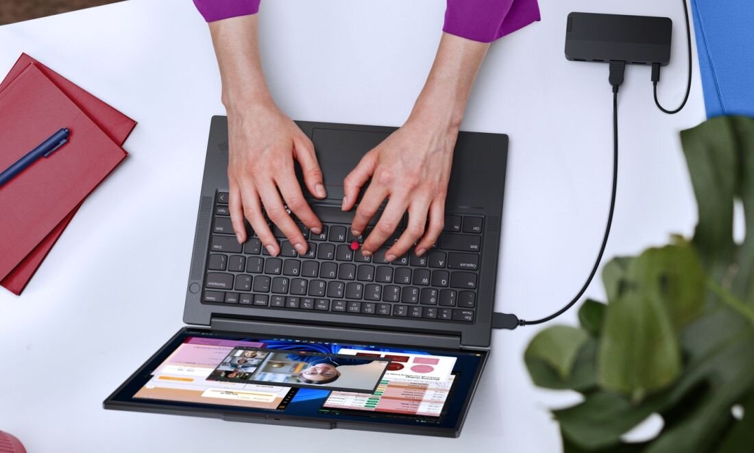 Osoba korzysta z laptopa Lenovo ThinkPad E14 Gen 7 z precyzyjnym touchpadem przy biurku z akcesoriami w biurze - Touchpad i TrackPoint
