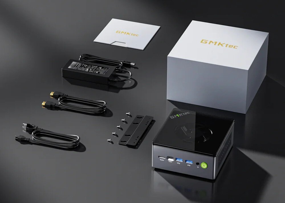 Komputer GMKTEC M7 Zestaw sprzedażowy z komputerem mini PC, zasilaczem, przewodami HDMI i zasilania, śrubkami montażowymi, uchwytem i instrukcją obok oryginalnego opakowania