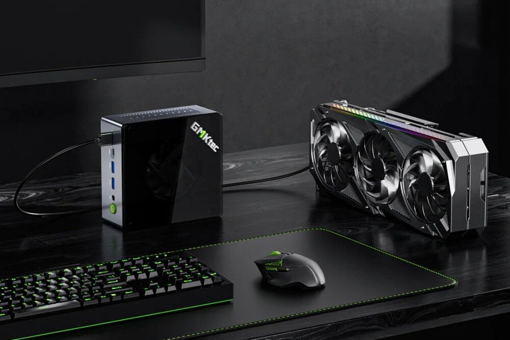 Komputer GMKTEC M7 Komputer mini PC połączony za pomocą przewodu z zewnętrzną kartą graficzną stojącą obok na biurku, widoczne klawiatura i mysz, złącze OcuLink, podłączenie kart graficznych