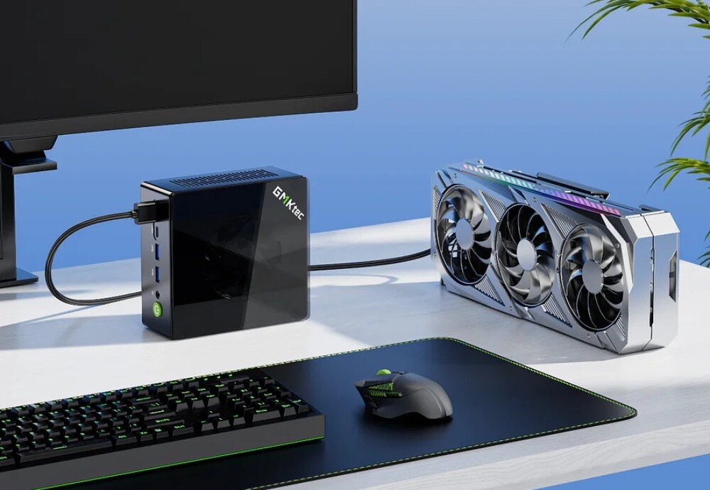 Komputer GMKTEC K8 Plus Komputer mini PC podłączony do zewnętrznej karty graficznej z trzema wentylatorami, stojący na biurku obok klawiatury, myszy i monitora, port OcuLink, zewnętrzna karta graficzna