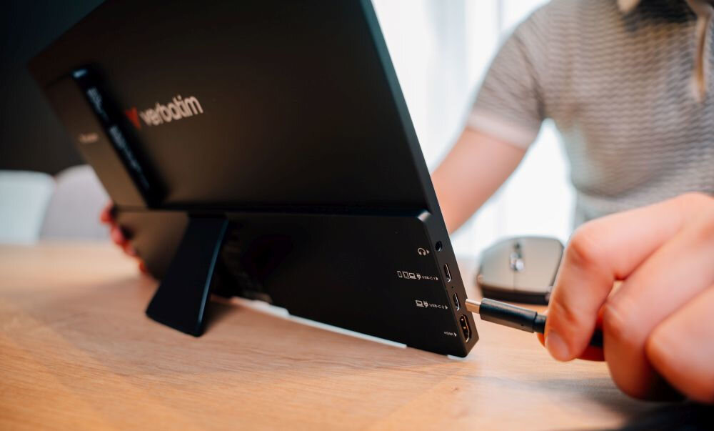 Monitor VERBATIM Light 14 cali FHD z powerbankiem 5000 mAh Czarny zbliżenie na porty w monitorze na biurku mężczyzna podłączający kabel do niego monitor przenośny USB-C HDMI kompatybilność szybka instalacja wygoda