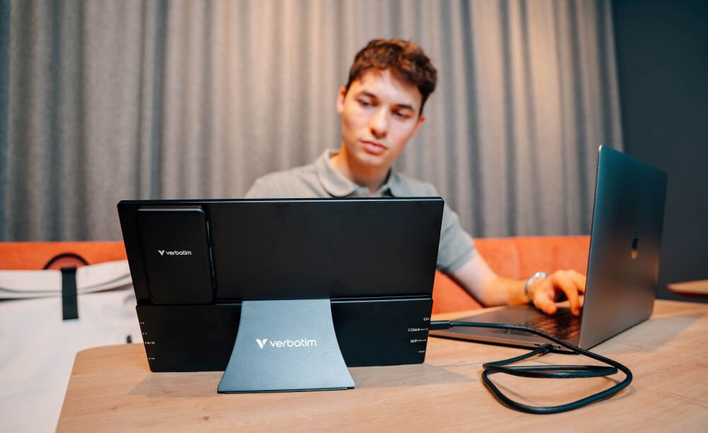 Monitor VERBATIM ALU 13.3 cala WUXGA z powerbankiem 5000mAh Czarny prezentacja monitora od tyłu podczas korzystania przez mężczyznę w pokoju obok laptop
