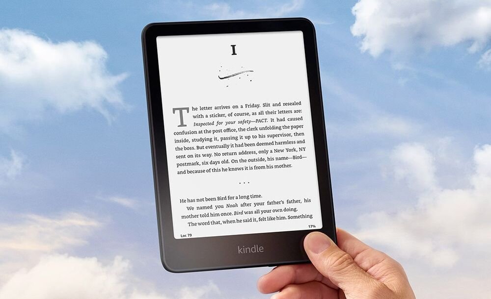 Osoba trzyma czytnik e-booków z widocznym tekstem na ekranie. Na dole urządzenia znajduje się napis \'kindle\'.