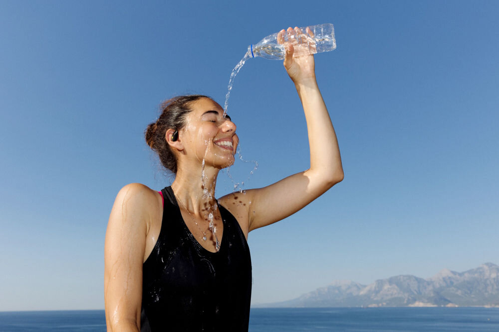 JBL Endurance Zone wodoodporność i pyłoszczelność IP68 odporność na pot i deszcz, osoba z założonymi słuchawkami oblewająca się wodą