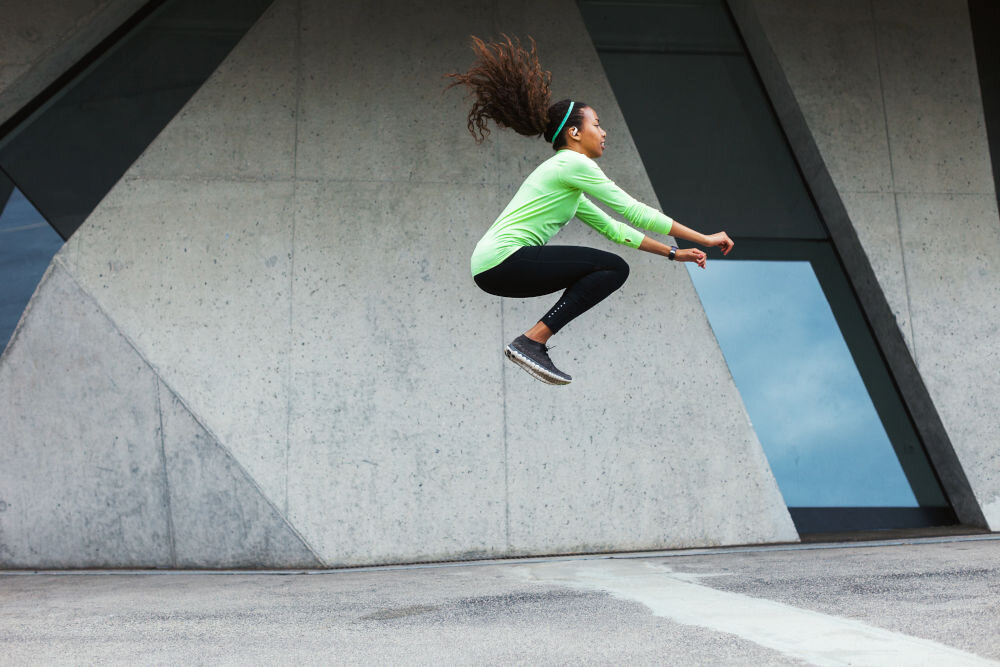 JBL Endurance Zone lekka konstrukcja silikonowa komfort i izolacja dźwięku, osoba z założonymi słuchawkami wykonująca skok wzwyż