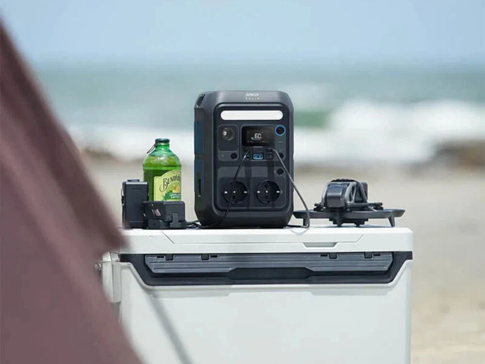 Stacja zasilania ANKER Solix C300X 288 Wh Bank energii + Panel solarny PS60 60W, ładowanie, AC, wymiary, panel, kartka, A4, stacja stoi na stole biwakowym nad morzem, w tle morze