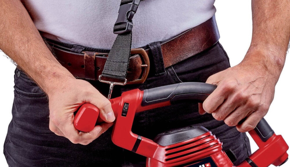 Odkurzacz do liści elektryczny EINHELL GC-EL 3000 E 3433320 osoba trzyma odkurzacz w dłoniach zbliżenie na uchwyt widoczny pasek ergonomicznie zaprojektowana rękojeść dopasowuje się do dłoni dodatkowy regulowany uchwyt dopasowanie pozycji chwytu do użytkownika kontrola nad urządzeniem precyzja pracy