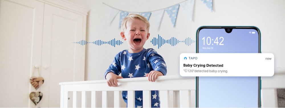 Dziecko w niebieskiej piżamie stoi w łóżeczku i płacze. Obok znajduje się smartfon z powiadomieniem: \'TAPO Baby Crying Detected C120 detected baby crying.\'