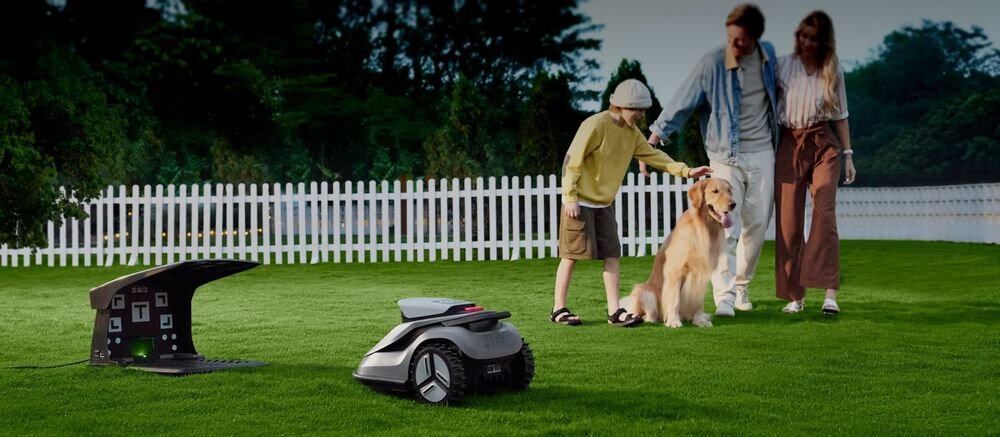 Robot koszący TERRAMOW V600 Bez przewodu ograniczającego Bluetooth/Wi-Fi 600 m2, robot koszący, kosiarka, ogród, trawnik, Robot koszący na trawniku przed rodziną z psem.   