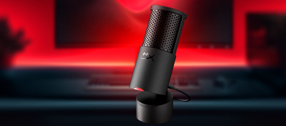 Mikrofon HYPERX SoloCast 2 Kardioidalny prezentacja mikrofonu pod kątem na rozmazanym tle biurka z monitorem i czerwoną poświatą