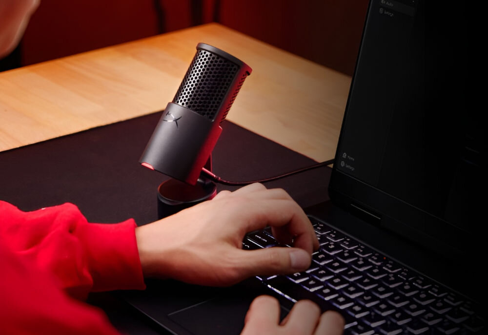 Mikrofon HYPERX SoloCast 2 Kardioidalny Mężczyzna siedzący przy biurku z laptopem i mikrofonem HyperX SoloCast 2 czysty szczegółowy dźwięk 24-bitowa głębia próbkowanie studyjna jakość