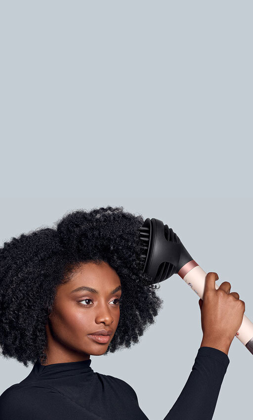 Modelka z afro stylizuje włosy przy pomocy dyfuzora używając multistylera Dyson Airwrap Coanda2x. Wersja mobile.