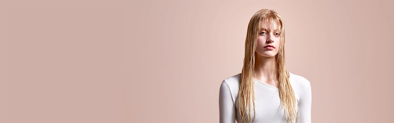 Modelka z wilgotnymi  blond włosami do ramion.