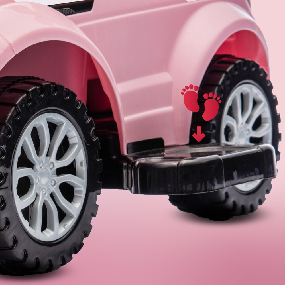 Różowy jeździk z dużymi czarnymi kołami i białymi felgami. Na stopniu widoczny jest symbol czerwonych stóp z czerwoną strzałką skierowaną w dół.