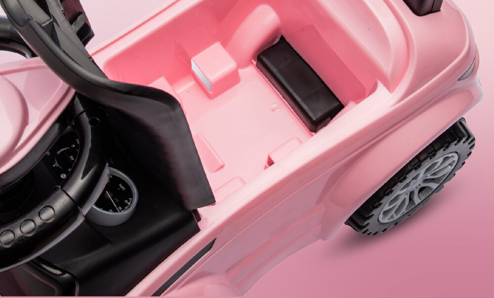 Różowy jeździk dziecięcy z czarną kierownicą i siedzeniem, posiadający czarne koła z szarymi felgami. Wnętrze jest przestronne z miejscem na nogi i elementami imitującymi deskę rozdzielczą.