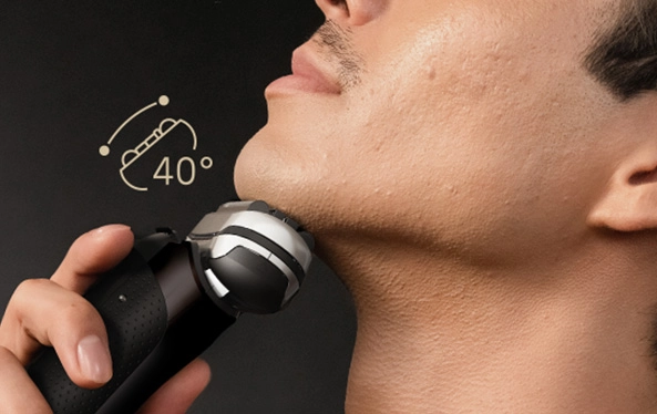 Mężczyzna goli się elektryczną golarką, starannie usuwając zarost z twarzy.