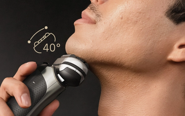 Mężczyzna goli się elektryczną golarką, starannie usuwając zarost z twarzy.