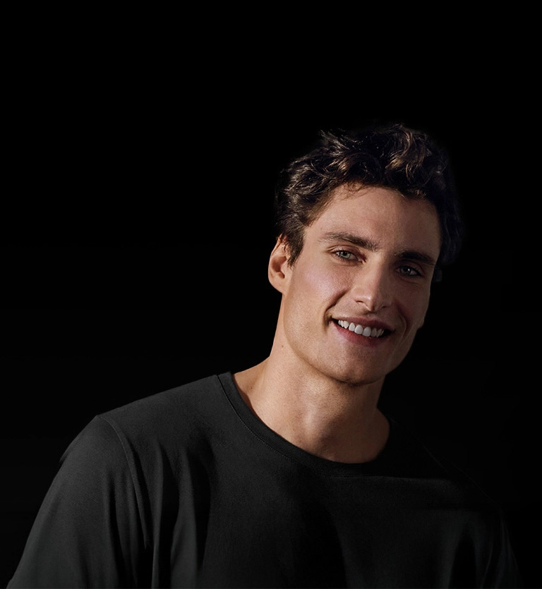 Mężczyzna w czarnym t-shircie z uśmiechem na twarzy.