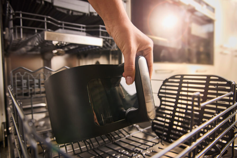Air Fryer Frytkownica beztłuszczowa BRAUN MultiFry 5 HF5073 osoba wkłada kosz i kratkę do zmywarki z 20 automatycznymi programami gotowania szuflada ma powłokę zapobiegającą przywieraniu ruszt można łatwo zdemontować szybkie i wygodne mycie oba elementy nadają się do mycia w zmywarce higieniczna czystość zachowanie urządzenia w optymalnym stanie