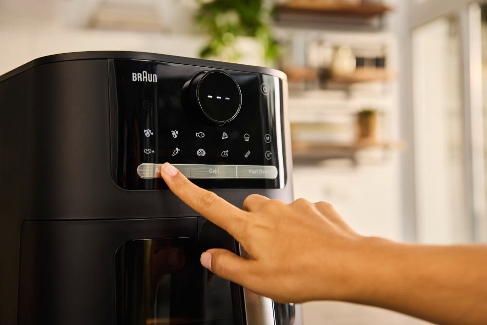 Air Fryer Frytkownica beztłuszczowa BRAUN MultiFry 5 HF5073 panel sterowania osoba wciska przycisk okrągły wyświetlacz z 20 automatycznymi programami gotowania wszechstronność gotowania satysfakcjonujące rezultaty panel dwa dotknięcia automatyczne ustawienie czasu i temperatury intuicyjny wyświetlacz 20 programów mrożone frytki ziemniaki warzywa kurczak ryby mięso ciasta podgrzewanie technologia cyrkulacji powietrza stylowy design