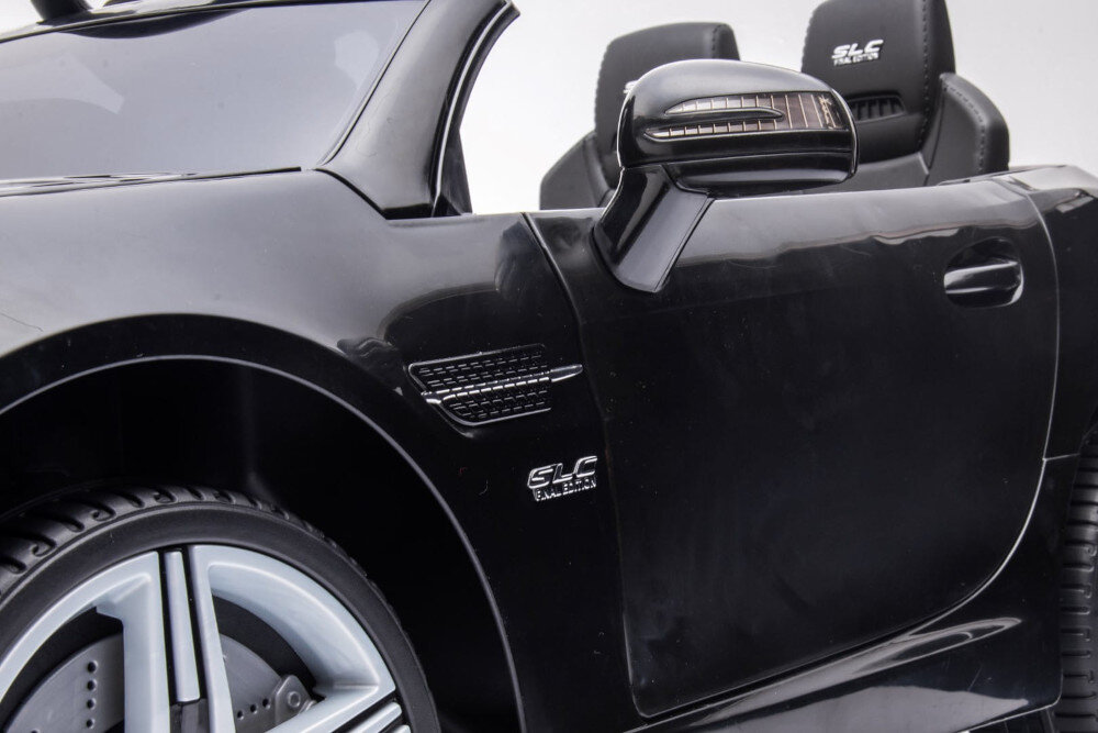 Czarny samochód dziecięcy z widocznym logo \'SLC\' na drzwiach i siedzeniach. Samochód ma lusterko boczne i szczegółowe wykończenia przy nadkolu.