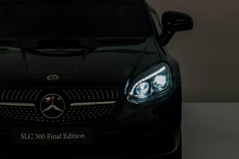 Czarny samochód dziecięcy z logo Mercedes na masce i świecącymi reflektorami. Na tabliczce widnieje napis \'SLC 300 Final Edition\'.