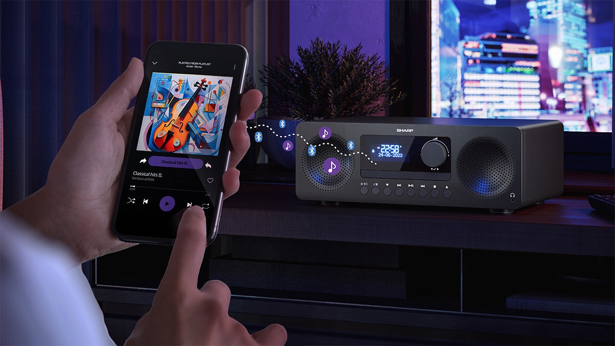 Wieża SHARP XL-B720D z łącznością Bluetooth 5.0 do smartfona i laptopa, wieża stojąca na komodzie, ręka trzymająca smartfon z muzyką