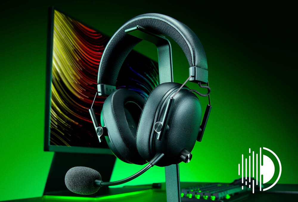 RAZER BlackShark V3 X HyperSpeed przyciski sterujące, pokrętło głośności, słuchawki wiszące na stojaku obok monitora