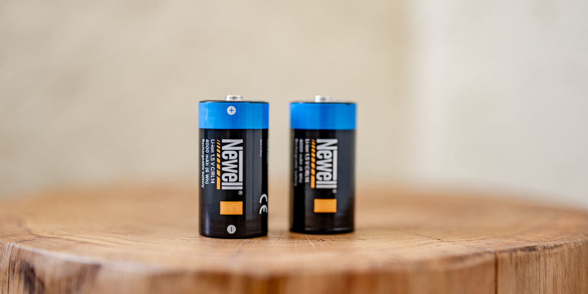 Akumulatorki NEWELL C/R14 USB-C 4000 mAh (2 szt.), zasilanie, pojemność, trwałość, jakość, zbliżenie na stojące pionowo akumulatory stojące na pniu drzewa
