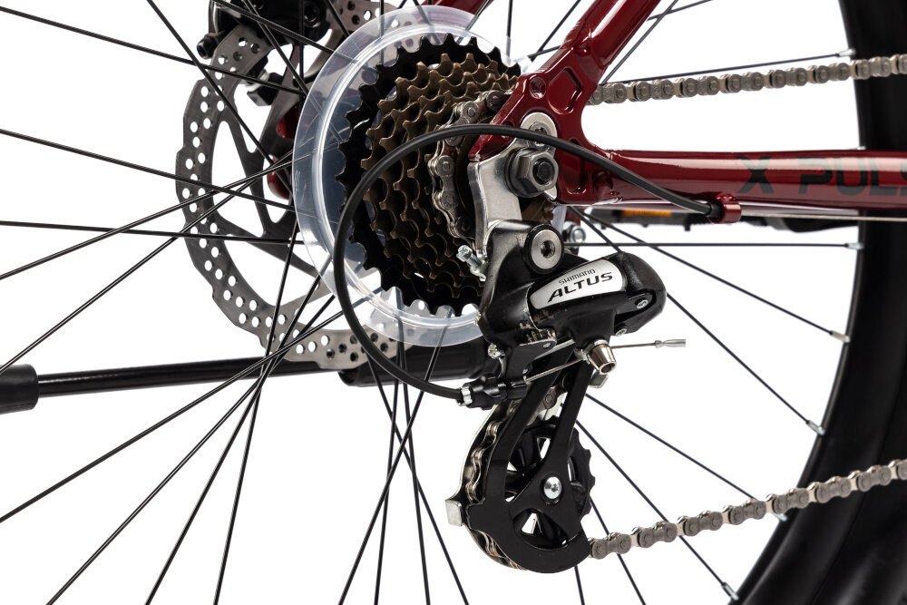 Rower młodzieżowy INDIANA X-Pulser 2.6 26 cale Czerwony zbliżenie na przerzutki 21 przełożeń przednia przerzutka SHIMANO Tourney do rekreacyjnej jazdy na rowerze duża wytrzymałość sprawne działanie zmiana biegów jest płynna i bezproblemowa tylna przerzutka SHIMANO Altus technologia Shadow przerzutka jest schowana i mniej narażona na uszkodzenia