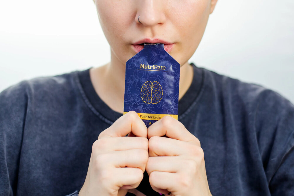 Suplement diety NUTRIRATE FoodforBrain 2 x 30 saszetek biała ściana osoba trzyma saszetkę w buzi niewielkie i łatwe do przenoszenia regularne wsparcie