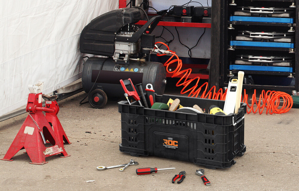 Kosz narzędziowy KETER ROC Pro Gear 1.0 warsztat kosz ustawiony na podłodze w koszu różne rzeczy wokół leża narzędzia ręczne otwarta górna konstrukcja płynność działania oszczędność czasu wygoda pracy