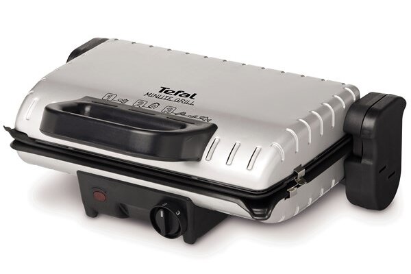 Grill elektryczny z metaliczną obudową i czarnymi elementami, z widocznym logo \'Tefal Minute Grill\' na pokrywie. Posiada pokrętło regulacji temperatury i przycisk zasilania na przednim panelu.