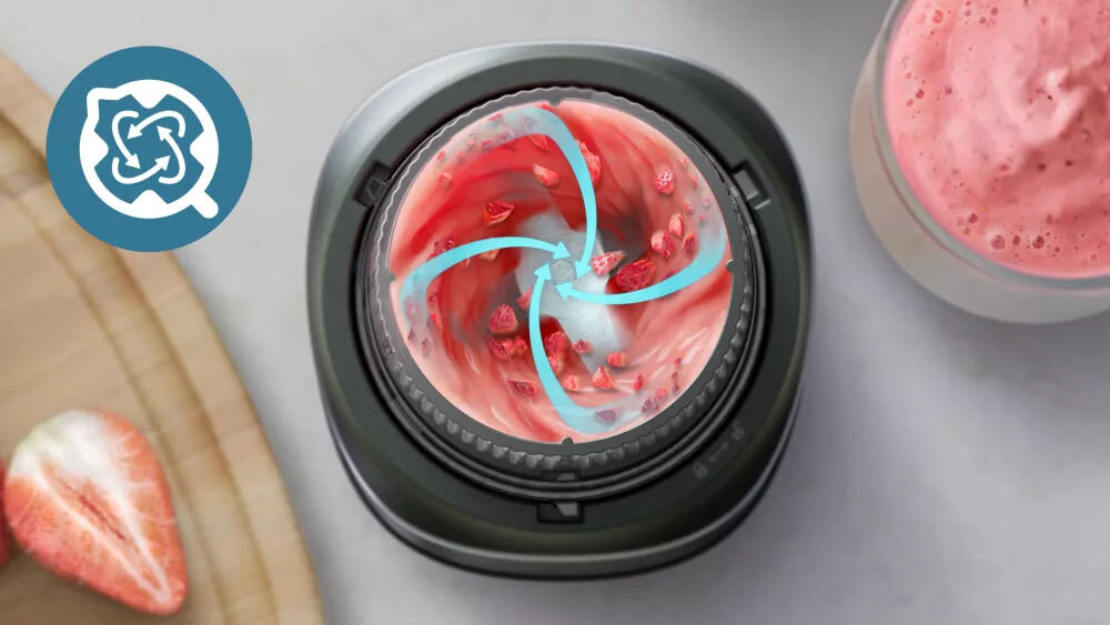 Obraz przedstawia blender kielichowy z widocznym wirującym różowym smoothie i kawałkami truskawek. Obok znajduje się logo z niebieskim symbolem przypominającym wir.