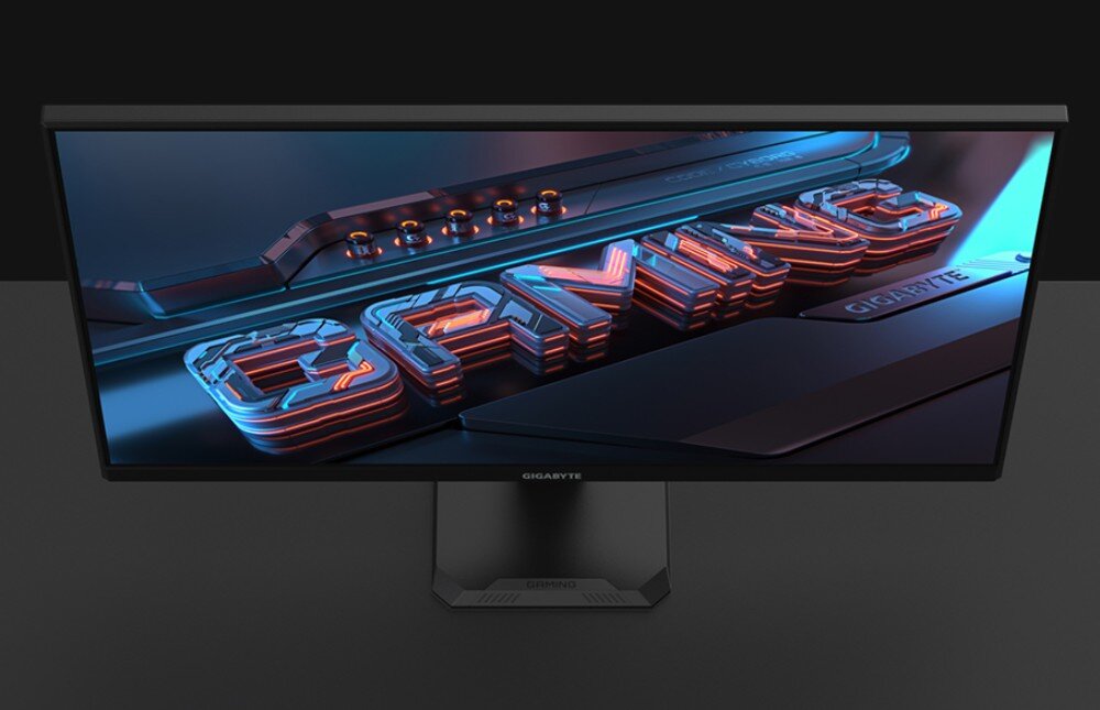 Monitor GIGABYTE GS27QA EU Monitor z napisem „GAMING” na ekranie pokazany od przodu pod lekkim kątem, na tle ciemnego biurka i ściany, ochrona wzroku, migotanie, niebieskie światło