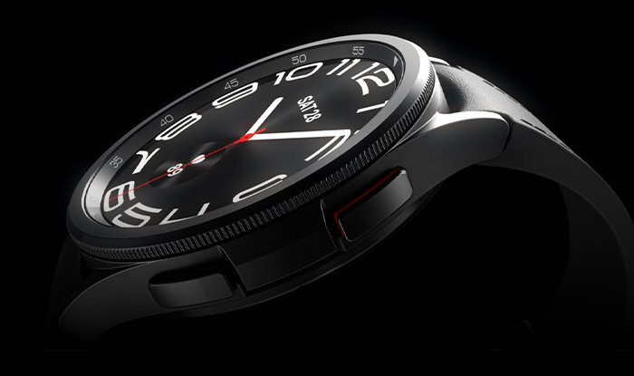 Zbliżenie na srebrny smartwatch z okrągłą tarczą, na której widoczne są cyfry i wskazówki. Na ekranie wyświetla się tekst \'SAT 28\'.