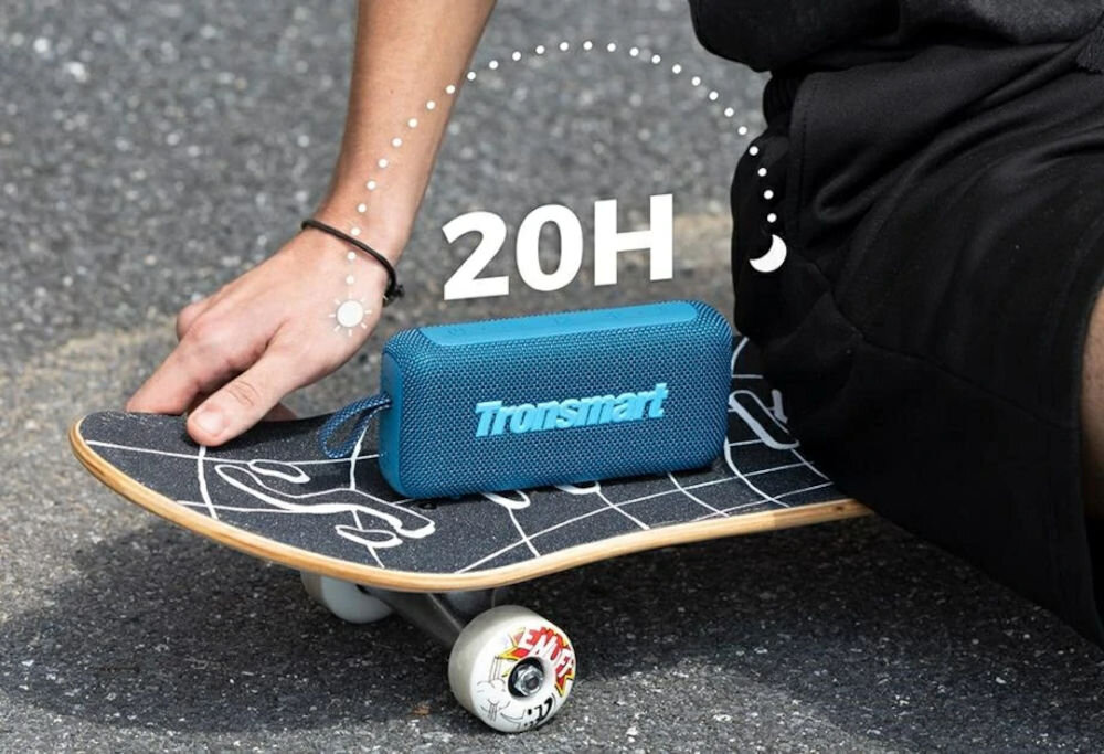 TRONSMART Trip 2 bateria 2600 mAh 20 godzin odtwarzania muzyka, Osoba siedząca na deskorolce z niebieskim głośnikiem Trip 2 na niej, nad głośnikiem biały napis 20H