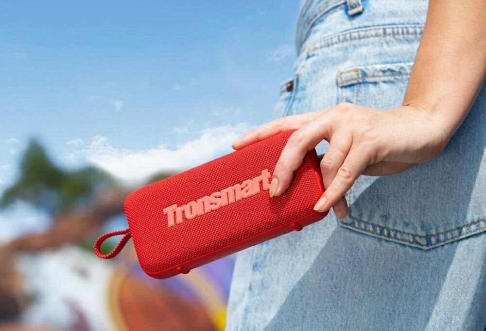 TRONSMART Trip 2 lekki przenośny pętla do przenoszenia, Osoba w jasnoniebieskich dżinsach trzymająca czerwony głośnik Trip 2