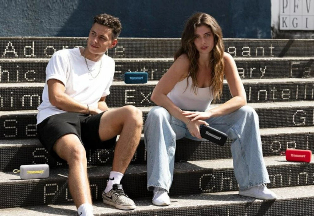 TRONSMART Trip 2 TWS stereo podłączenie dwóch urządzeń, Dwie osoby siedzące na schodach z czterema głośnikami Trip 2