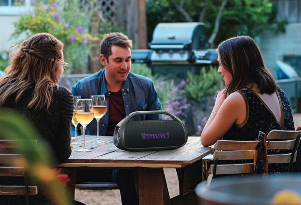 Głośnik mobilny TRONSMART Bang 2 — personalizacja EQ, aplikacja Tronsmart, kontrola dźwięku, osoby siedzące przy stoliku na którym stoi głośnik