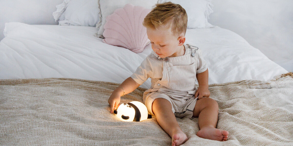 Lampka nocna INNOGIO GIOsleepy Panda GIO-143, oświetlenie, zasypianie, silikon, BPA, dziecko bawi się lampką panda na łóżku