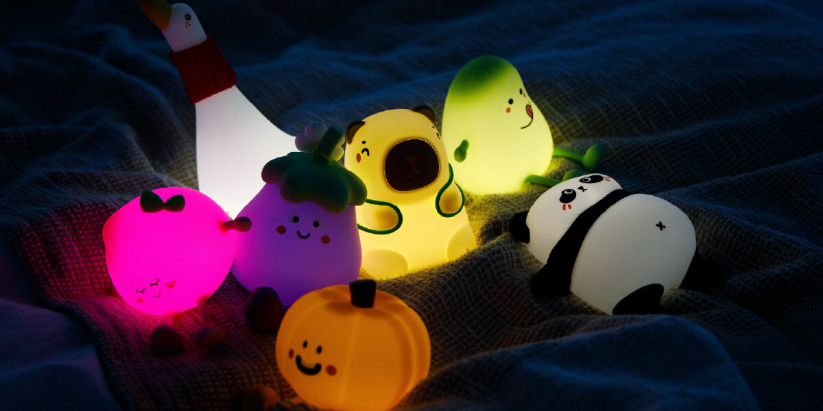 Lampka nocna INNOGIO GIOpumpkin Dynia GIO-146, dotyk, poziomy, ciepło, światło, lampki różnego rodzaju w tym GIOpumpkin leżą na łóżku w pełnej ciemności i świecą