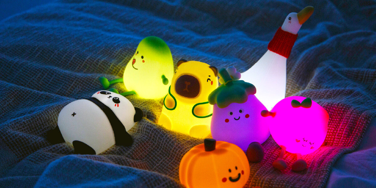 Lampka nocna INNOGIO GIOduck Kaczka GIO-145, wsparcie, zasypianie, oswoić, przyjazna, różnego rodzaju lampku w tym gioduck leżą na łóżku w ciemności świecąc